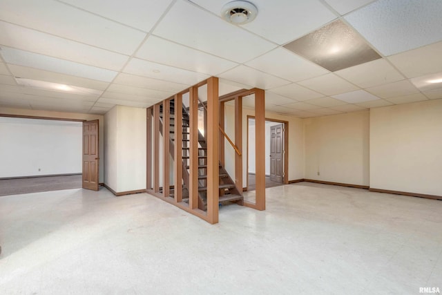 finished below grade area featuring tile patterned floors, stairway, baseboards, and a drop ceiling