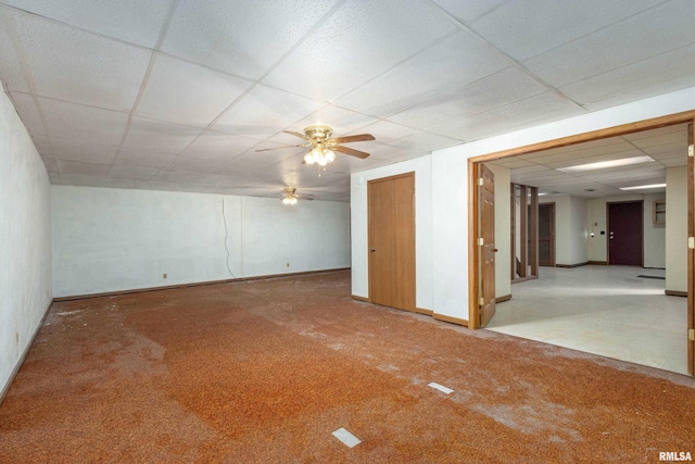 carpeted empty room featuring a drop ceiling, baseboards, and ceiling fan