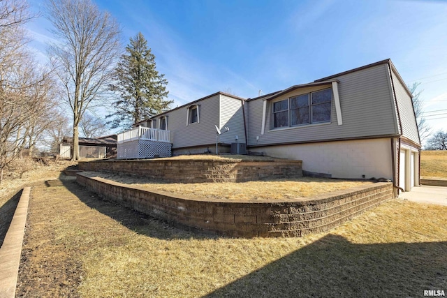 rear view of house featuring a garage, a deck, central AC unit, and concrete driveway