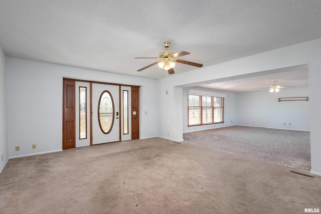 unfurnished living room with carpet flooring, a textured ceiling, and a ceiling fan