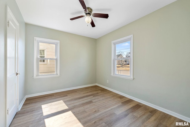 spare room with baseboards, light wood-style floors, and a ceiling fan