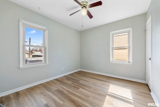 spare room with a ceiling fan, light wood-style floors, and baseboards