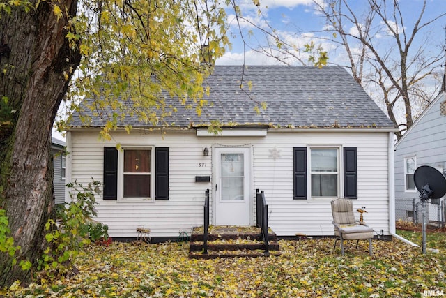 bungalow-style home featuring roof with shingles and fence