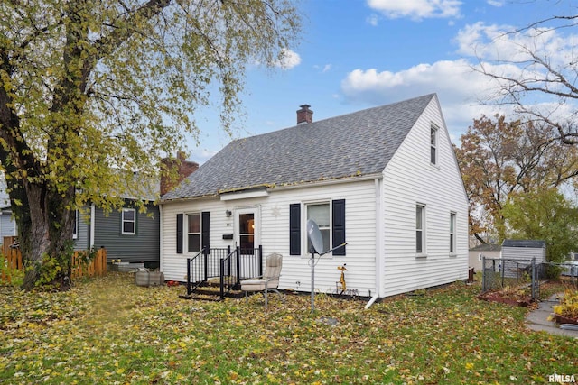 view of front of home featuring a front lawn, a shingled roof, a chimney, and fence