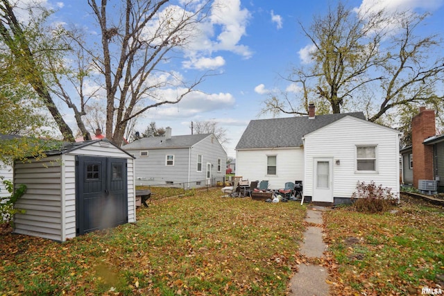 rear view of property featuring a storage unit, an outbuilding, central AC, and a chimney