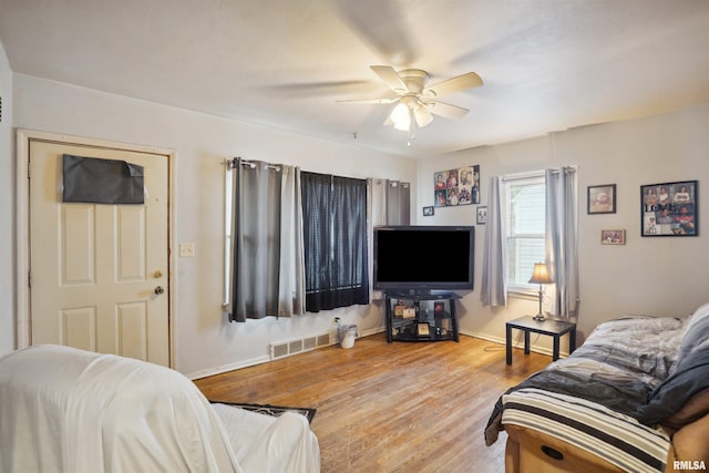 living area with visible vents, baseboards, wood finished floors, and a ceiling fan