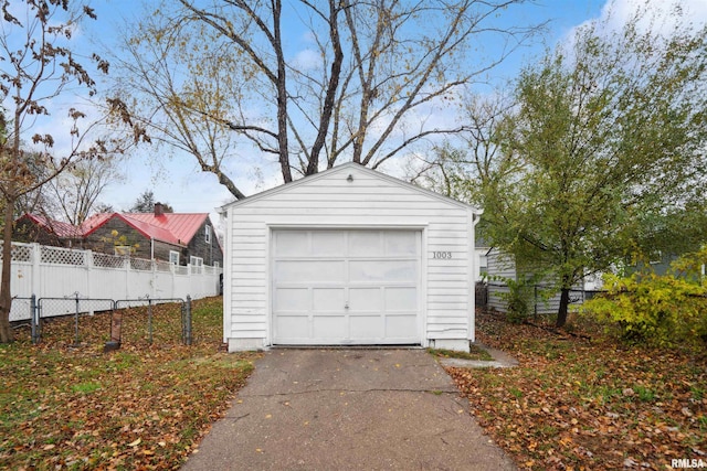 detached garage featuring aphalt driveway and fence