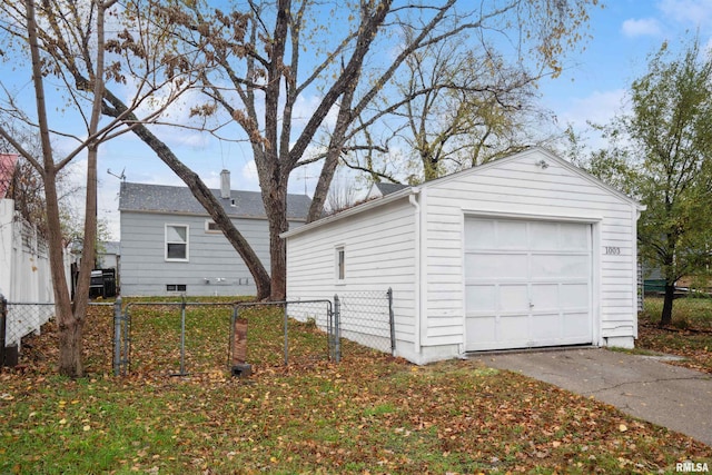 detached garage featuring driveway and fence