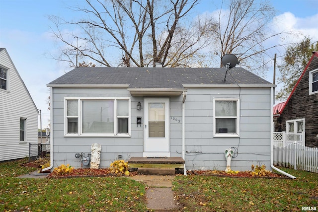 bungalow featuring a shingled roof, a front lawn, and fence