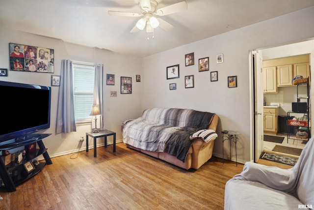 living room featuring baseboards, a ceiling fan, and light wood finished floors