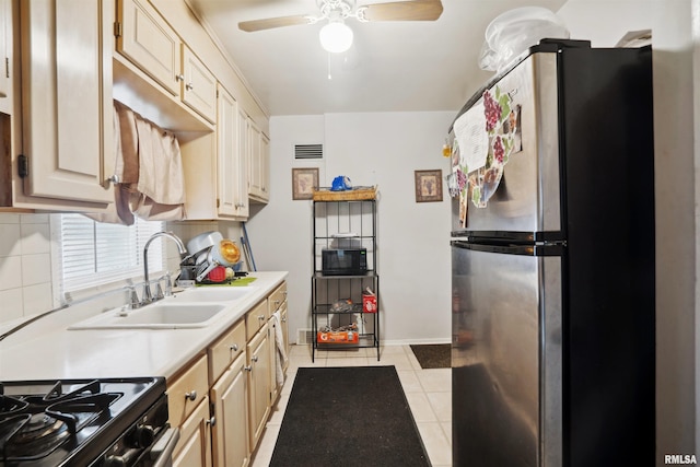 kitchen with visible vents, freestanding refrigerator, ceiling fan, a sink, and light countertops