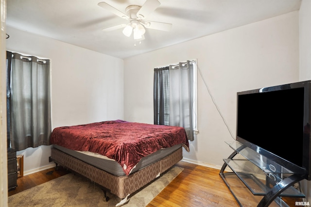 bedroom featuring ceiling fan, baseboards, and wood finished floors