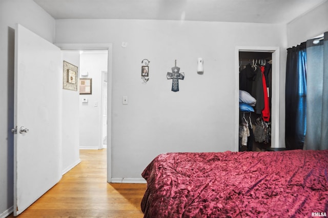 bedroom with a closet, baseboards, a walk in closet, and light wood-style floors