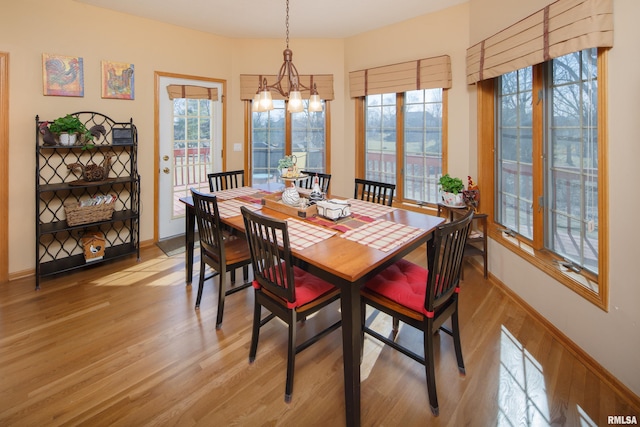 dining area with baseboards, light wood-style floors, and a chandelier