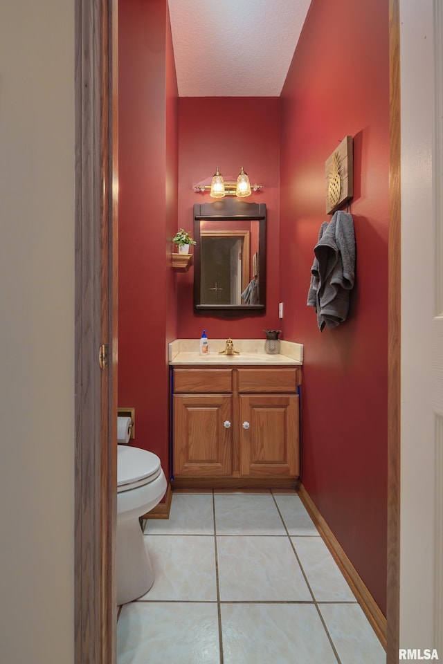 bathroom featuring vanity, baseboards, tile patterned flooring, a textured ceiling, and toilet