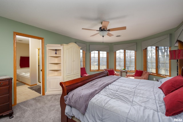 bedroom featuring connected bathroom, light colored carpet, and ceiling fan