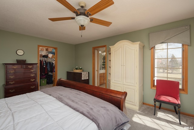 bedroom featuring light carpet, a closet, connected bathroom, baseboards, and a spacious closet