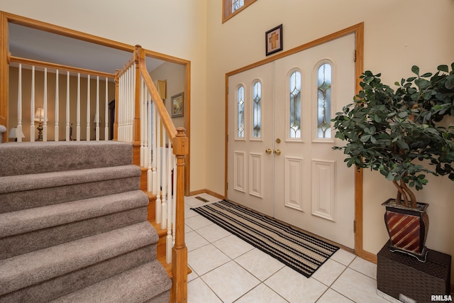 foyer featuring light tile patterned flooring, stairs, and baseboards