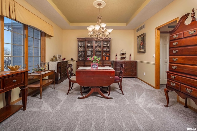 dining room featuring carpet, baseboards, visible vents, a tray ceiling, and a chandelier