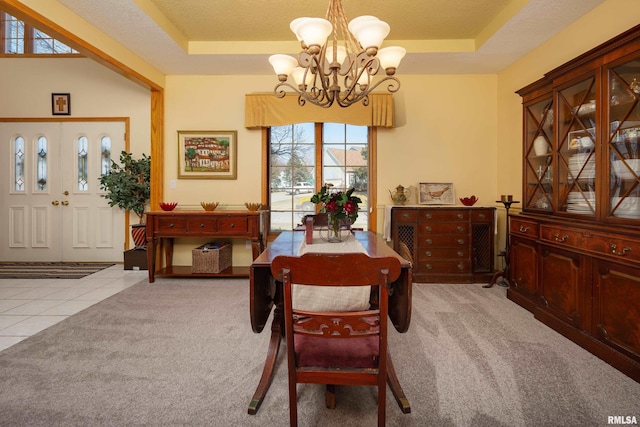 tiled dining room with a tray ceiling, a notable chandelier, carpet, and a textured ceiling