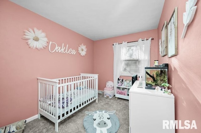 carpeted bedroom with a crib and baseboards