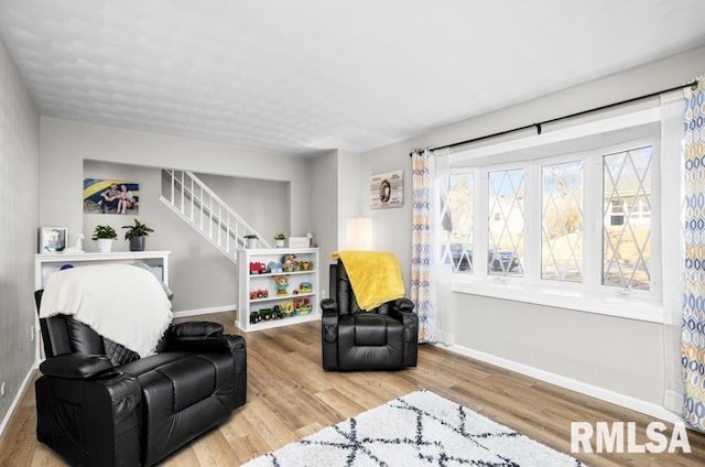 living area with stairway, wood finished floors, and baseboards