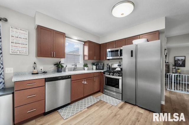 kitchen with a sink, stainless steel appliances, light countertops, and light wood finished floors