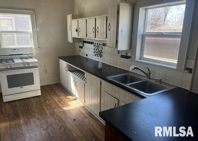 448 N 3rd Ave, Canton, IL 61520 - kitchen featuring white gas range, dark wood-style flooring, dark countertops, decorative backsplash, and white cabinets
