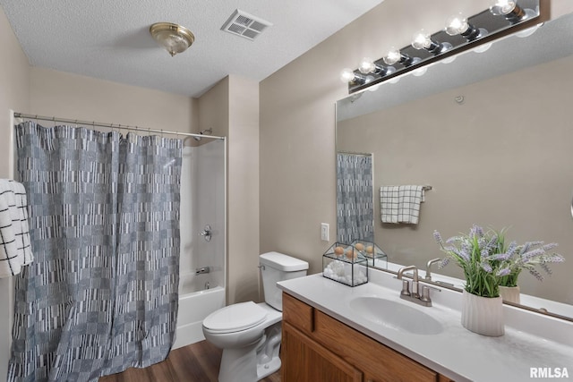 bathroom featuring visible vents, toilet, vanity, wood finished floors, and a textured ceiling