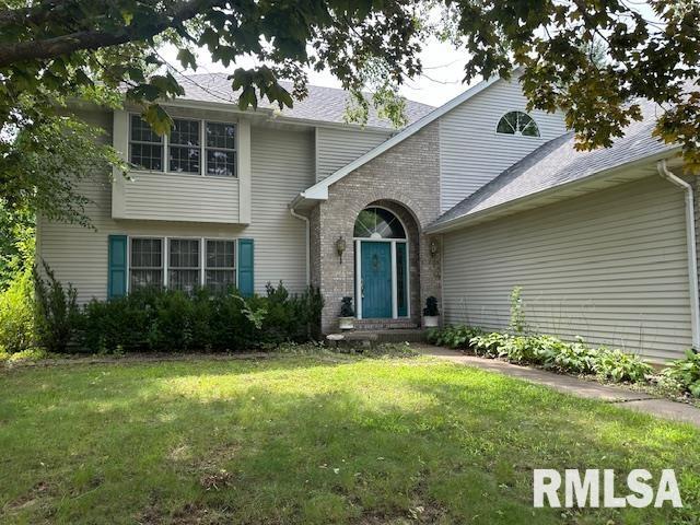 view of front facade with brick siding and a front lawn