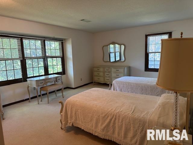 bedroom with a textured ceiling, baseboards, and light carpet