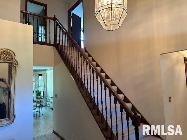 stairway with a notable chandelier and a towering ceiling