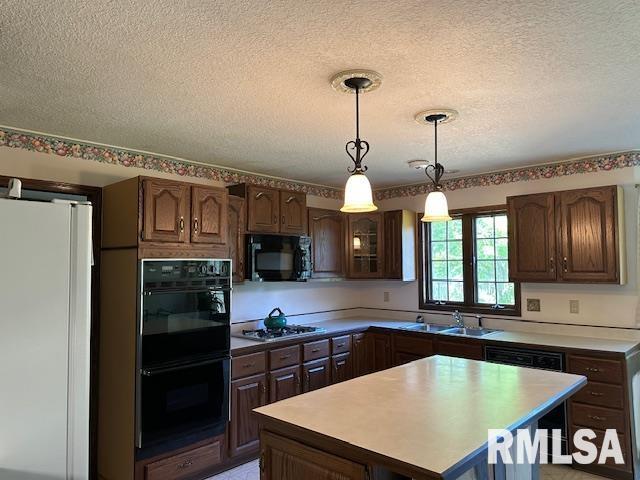 kitchen with hanging light fixtures, a textured ceiling, black appliances, and a sink