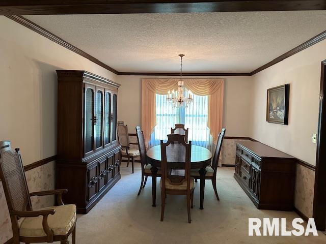 dining room with a textured ceiling, a chandelier, and wainscoting