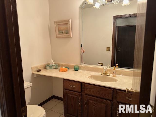 bathroom featuring tile patterned floors, toilet, an inviting chandelier, baseboards, and vanity