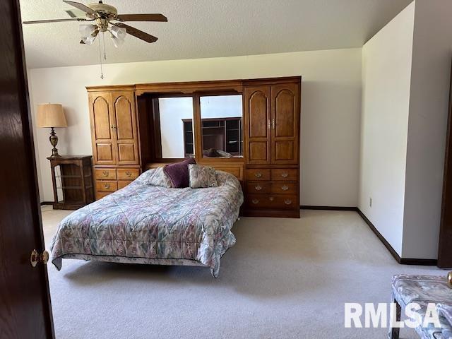 bedroom featuring light carpet, a textured ceiling, baseboards, and a ceiling fan