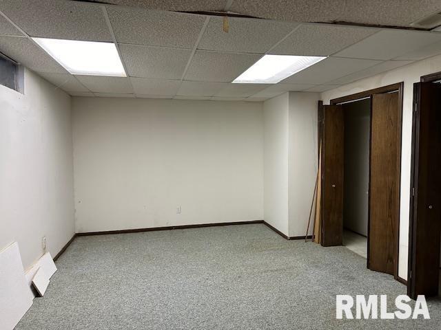 interior space featuring a drop ceiling, baseboards, light carpet, and visible vents