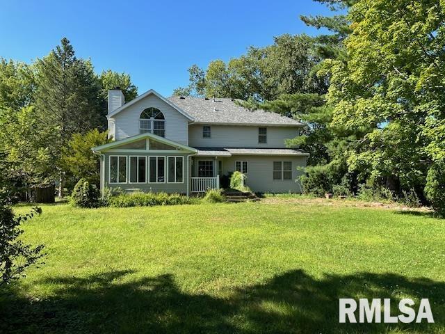 rear view of property with a yard, a chimney, and a sunroom