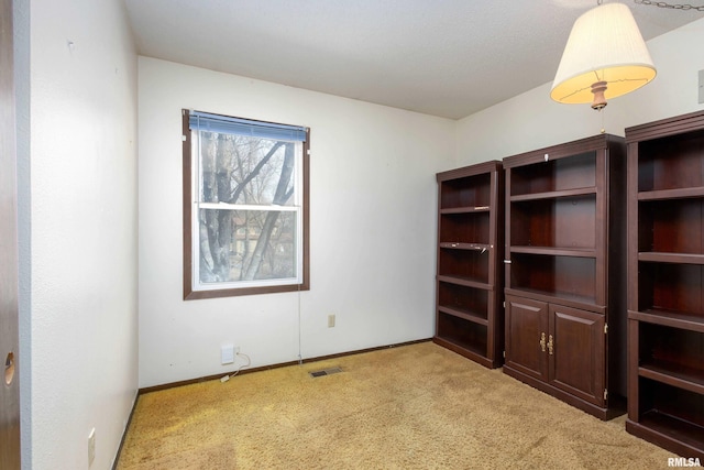 empty room with light carpet, visible vents, and baseboards