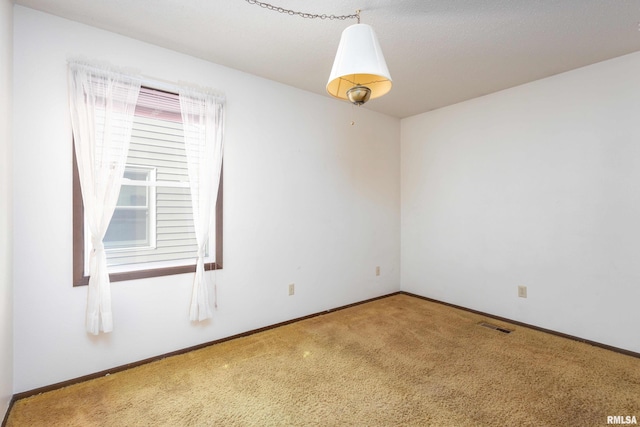 carpeted empty room featuring visible vents and baseboards