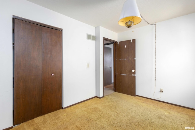 unfurnished bedroom featuring baseboards, visible vents, a closet, and light carpet