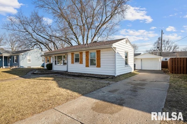 view of front of house featuring an outbuilding, a front lawn, a detached garage, fence, and concrete driveway