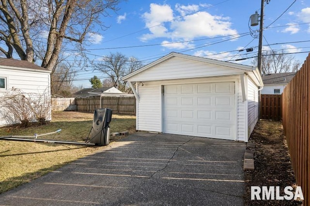 detached garage featuring fence and driveway