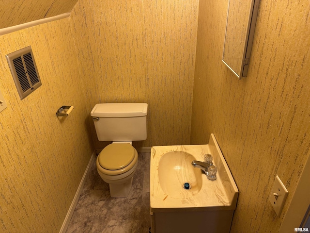 half bath featuring visible vents, toilet, vanity, and baseboards