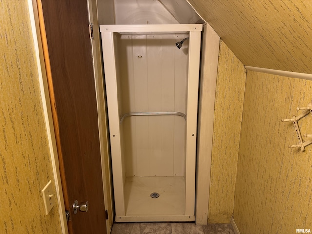 bathroom featuring elevator, walk in shower, and vaulted ceiling