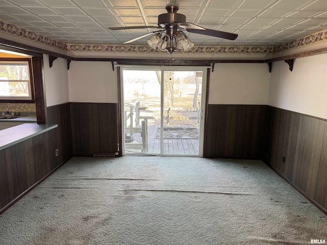 unfurnished room featuring an ornate ceiling, wood walls, and wainscoting