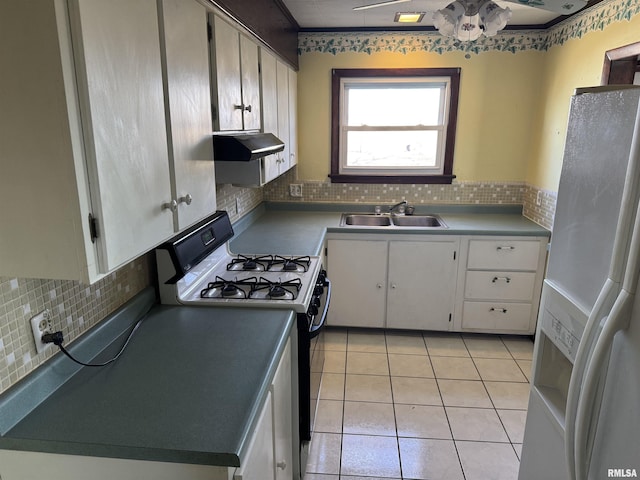 kitchen with light tile patterned floors, a sink, white refrigerator with ice dispenser, under cabinet range hood, and range with gas cooktop