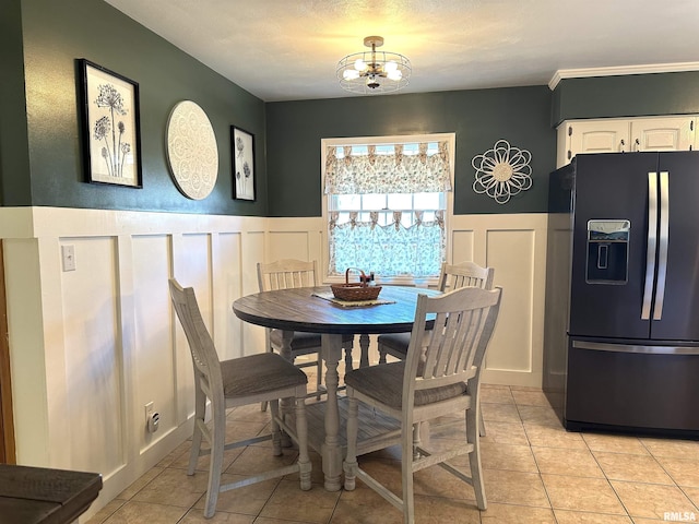 dining area with a notable chandelier, light tile patterned flooring, and wainscoting