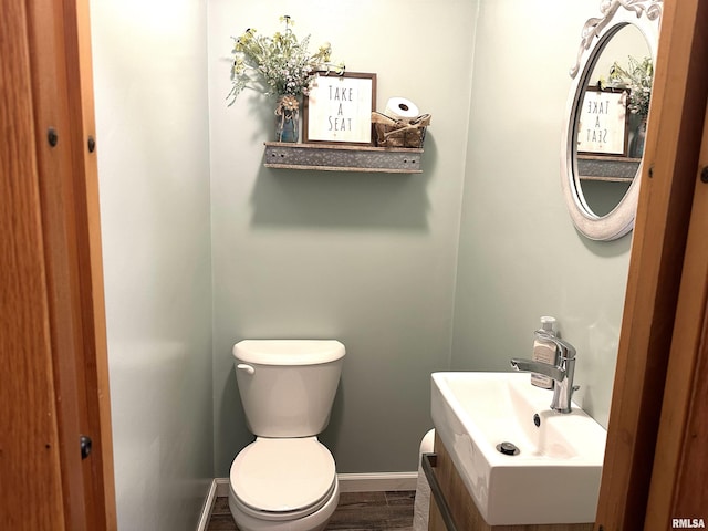 bathroom with toilet, vanity, and baseboards