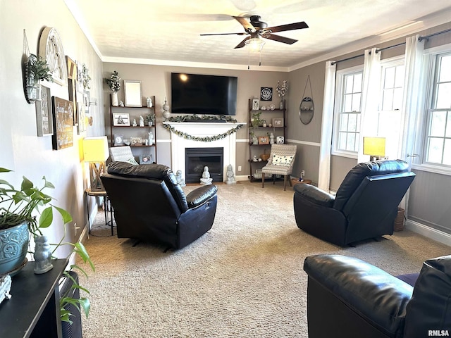 living area featuring a glass covered fireplace, ornamental molding, carpet floors, and ceiling fan